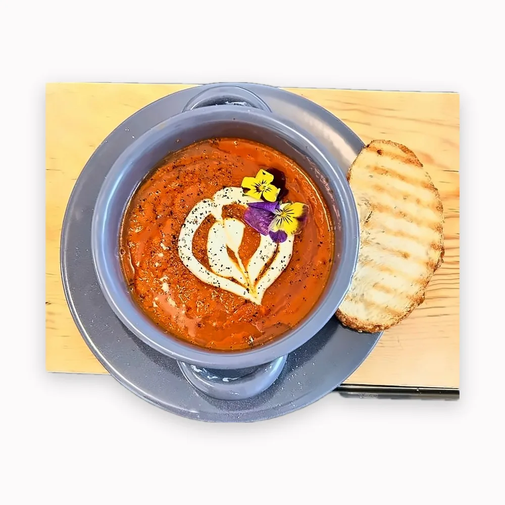 Crema de tomate con flores comestibles y pan tostado